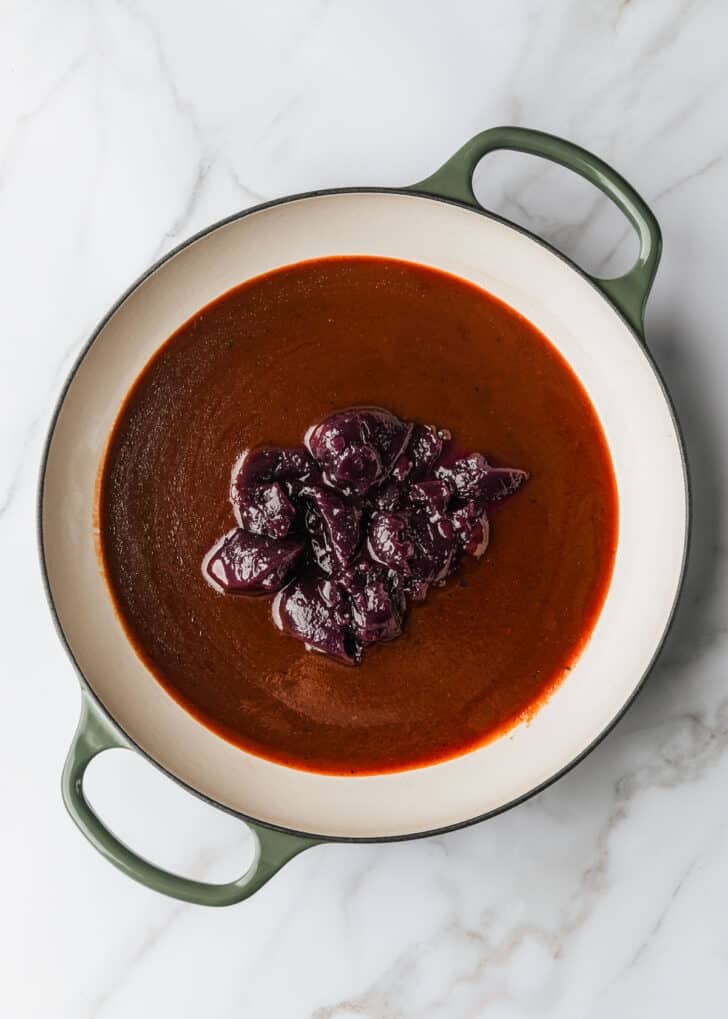 A pan of BBQ sauce and grape jelly on a white counter.