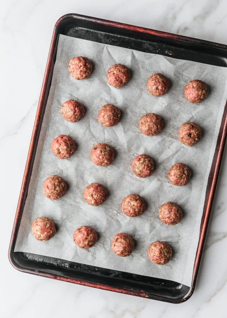 A sheet pan of raw meatballs for BBQ grape jelly meatballs.