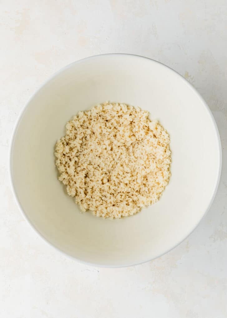 A white bowl of breadcrumbs and milk on a white counter.