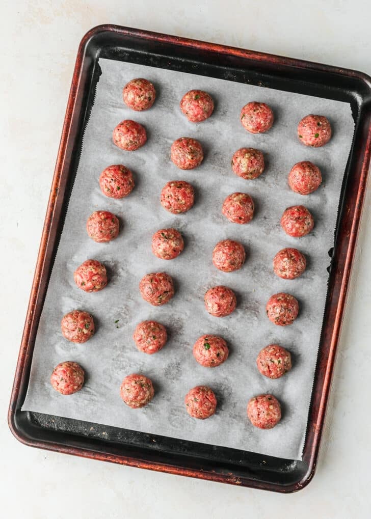 A sheet pan of raw Italian meatballs.