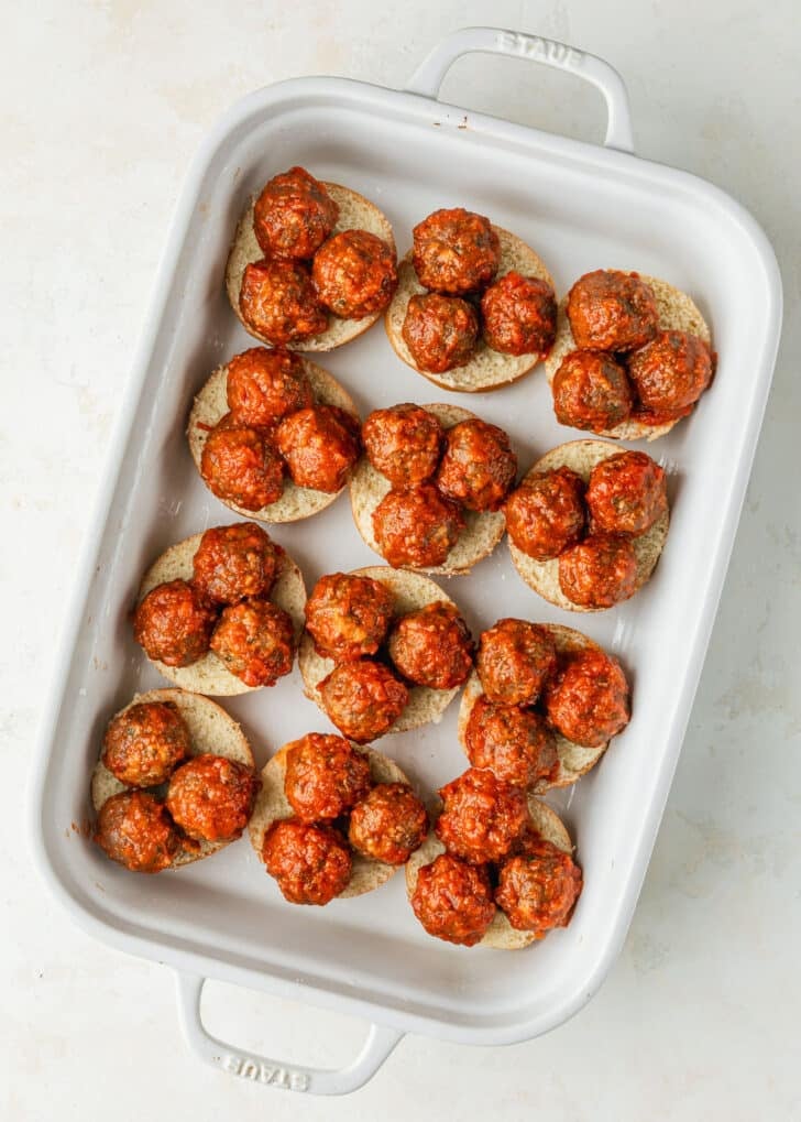 A white pan of rolls and meatballs on a tan counter.