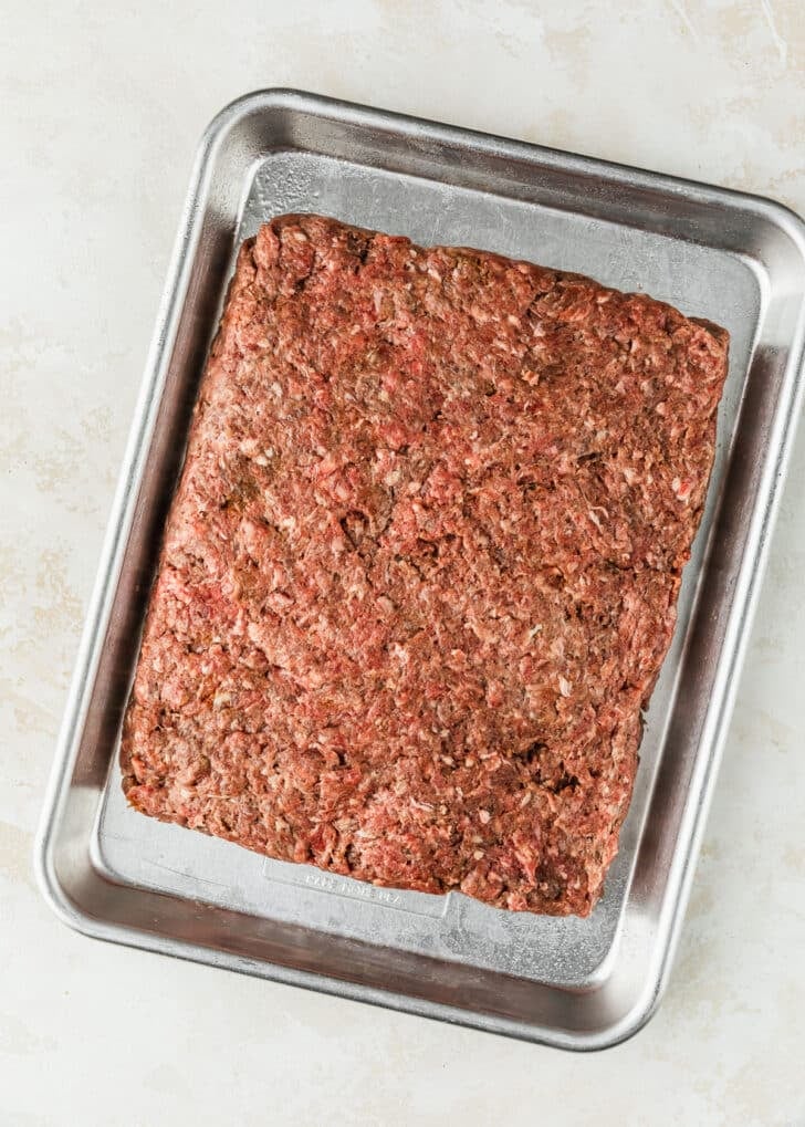A sheet pan with a rectangle of ground beef mixture.