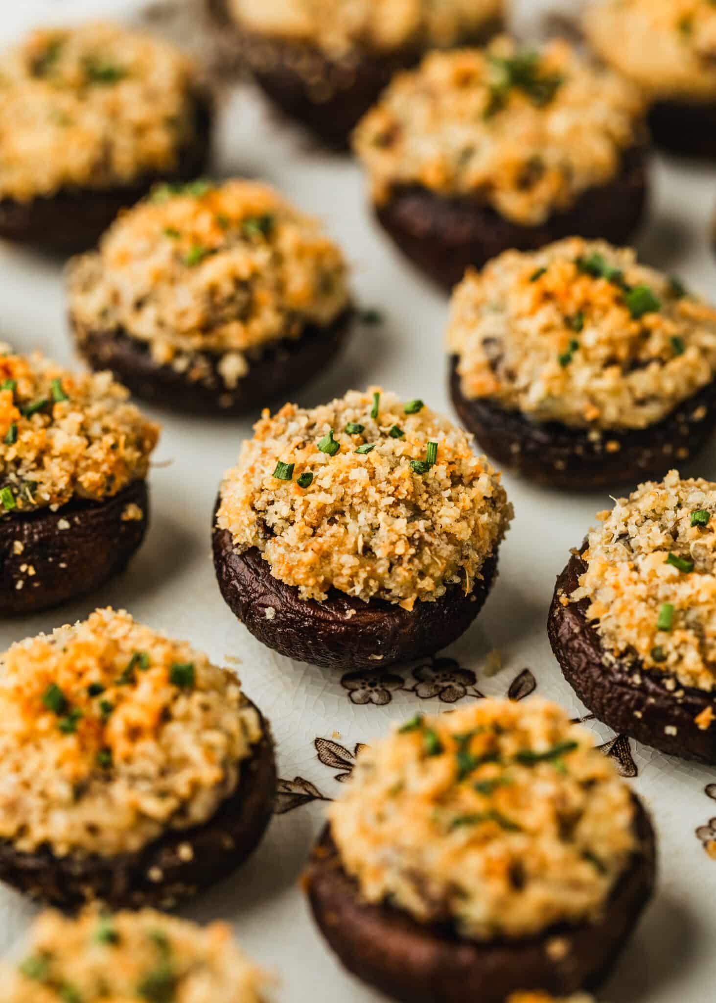 Rows of boursin cheese stuffed mushrooms with Panko topping on a white platter.