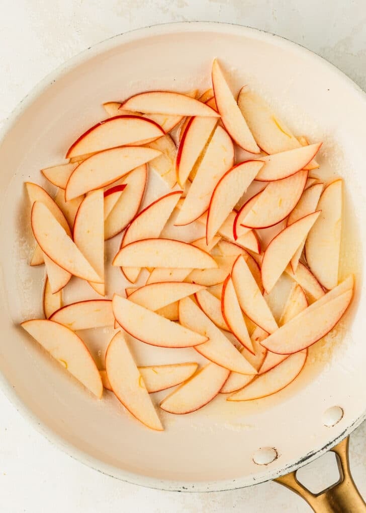 A white pan of apples and butter on a tan table.