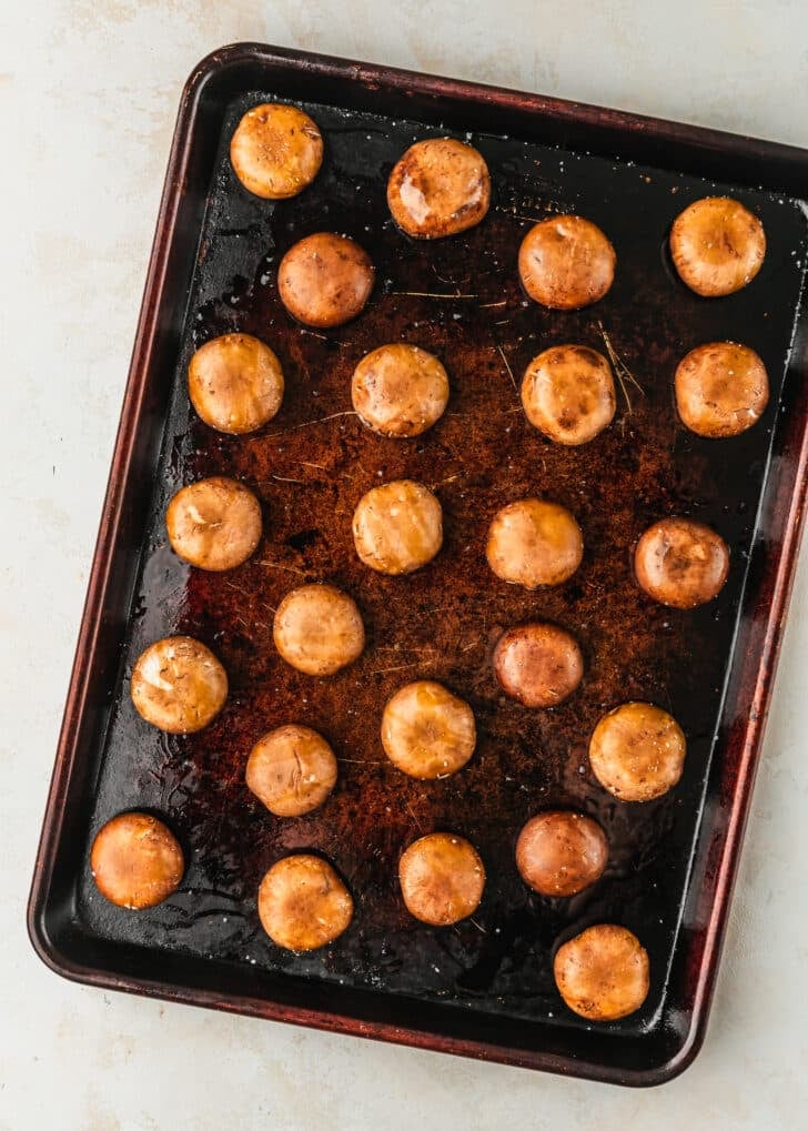 A sheet pan of mushrooms on a tan counter.
