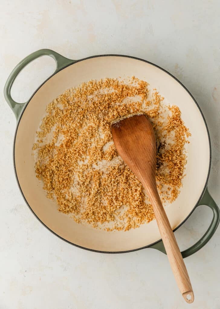 A pan of toasted Panko breadcrumbs with a wood spoon on a tan counter.