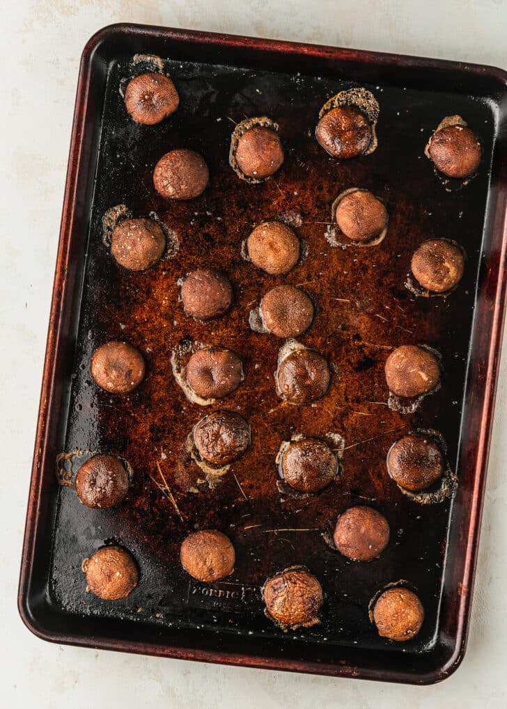 A sheet pan of roasted creminis on a tan counter.
