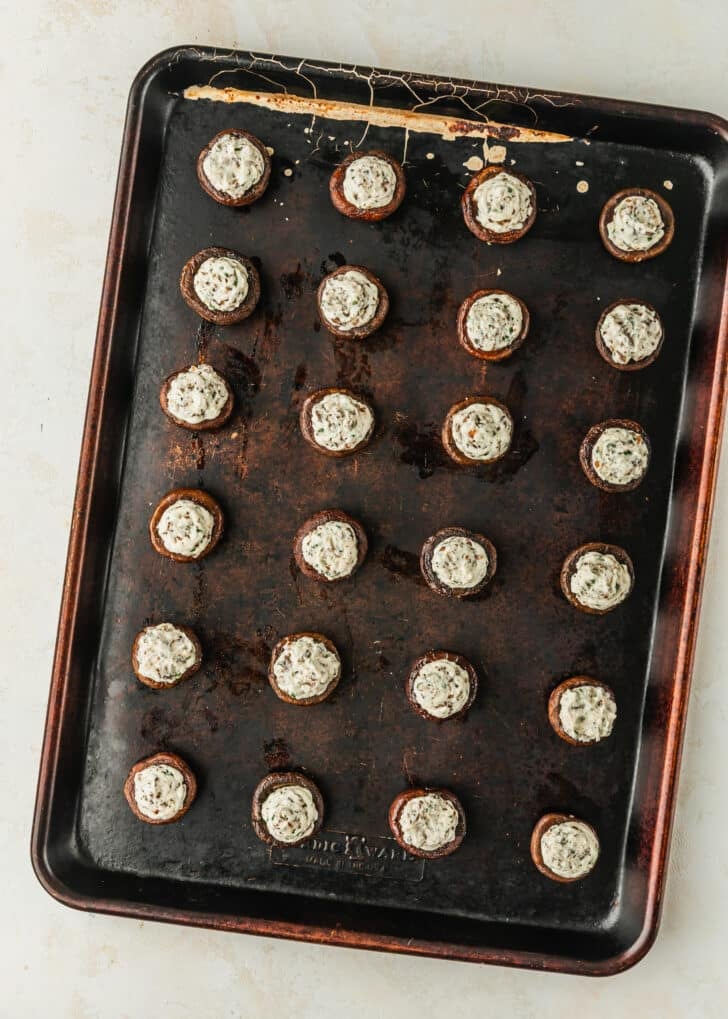 A pan of boursin cheese stuffed mushrooms on a tan counter.