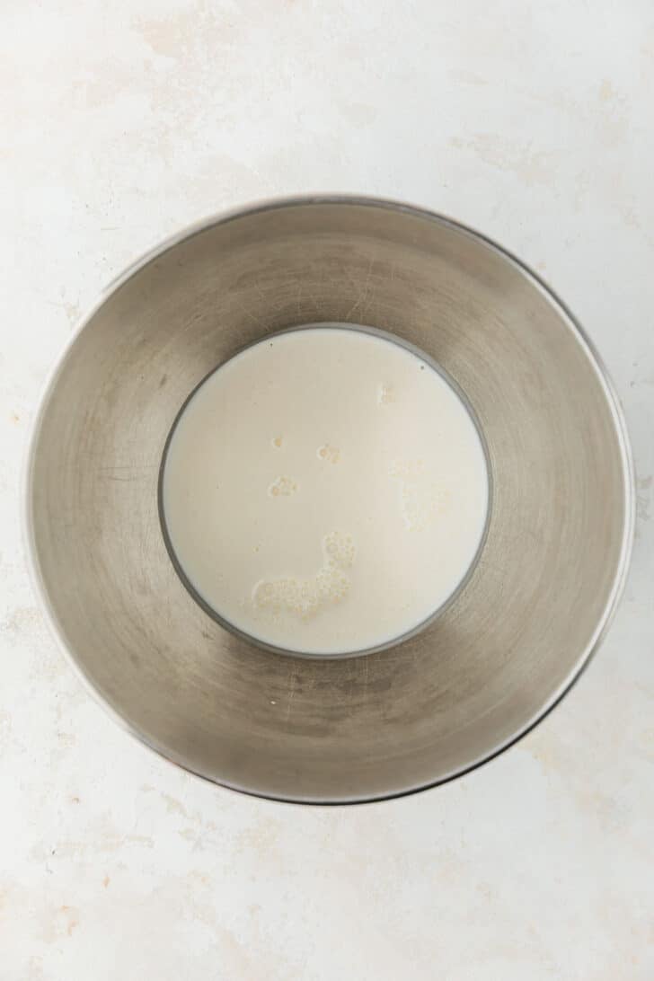 A silver bowl of whipping cream on a tan counter.