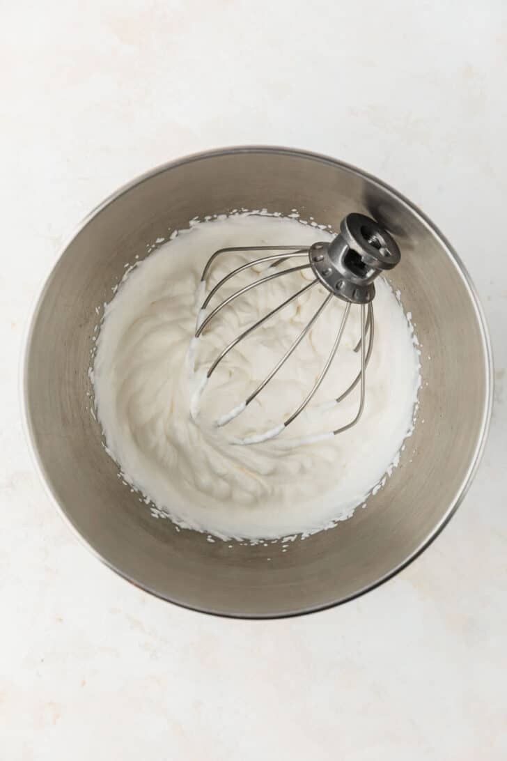 A silver bowl of whipped cream on a tan counter.