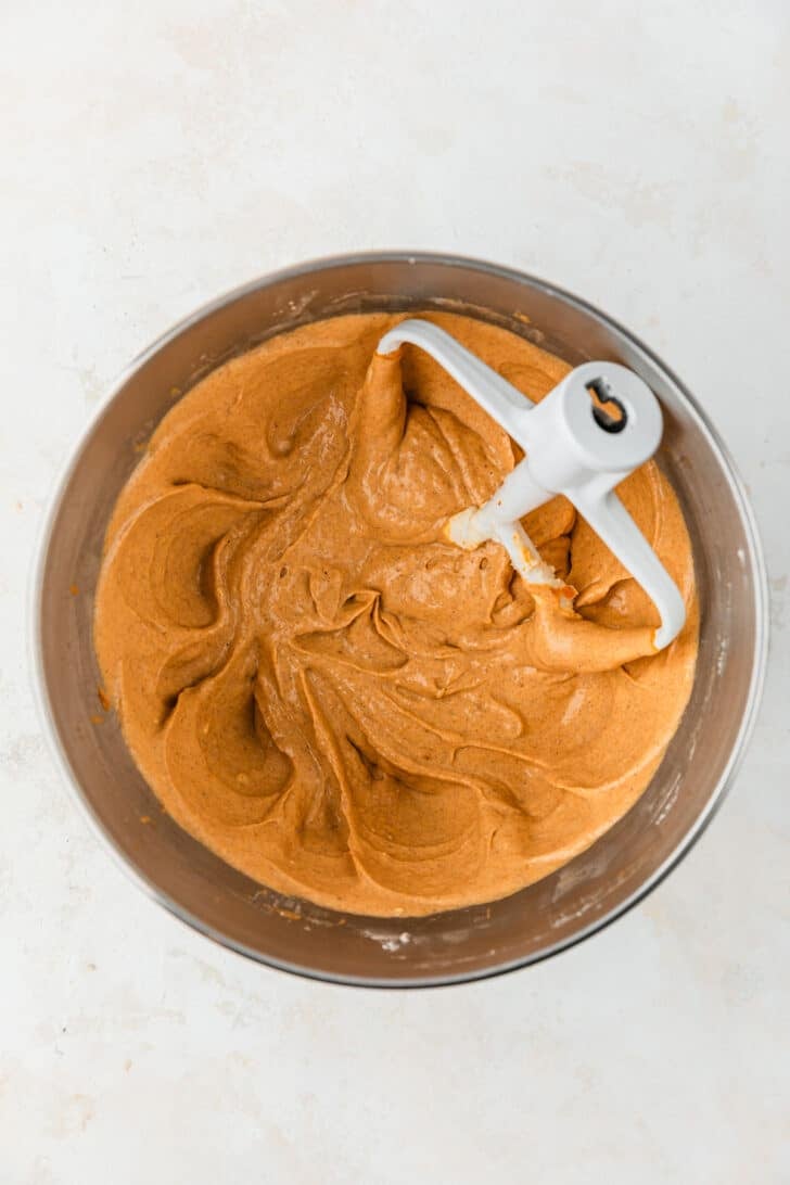 A silver bowl of pumpkin pie dip mixture on a beige table.