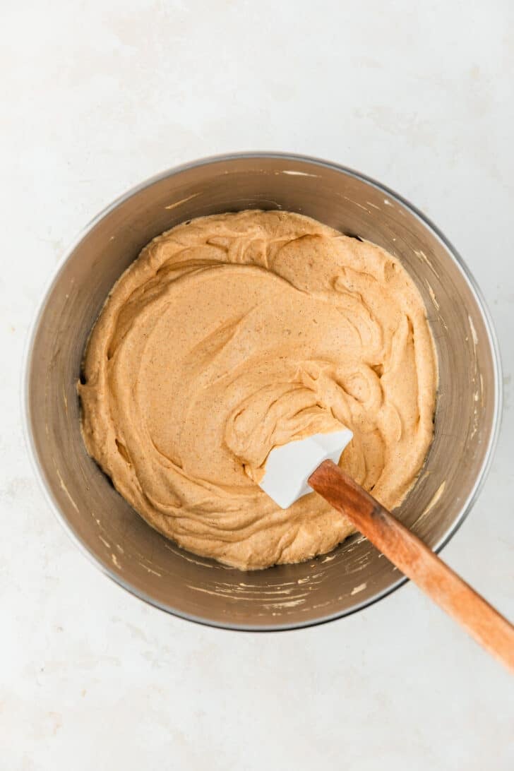 A silver bowl of pumpkin pie dip on a beige counter.