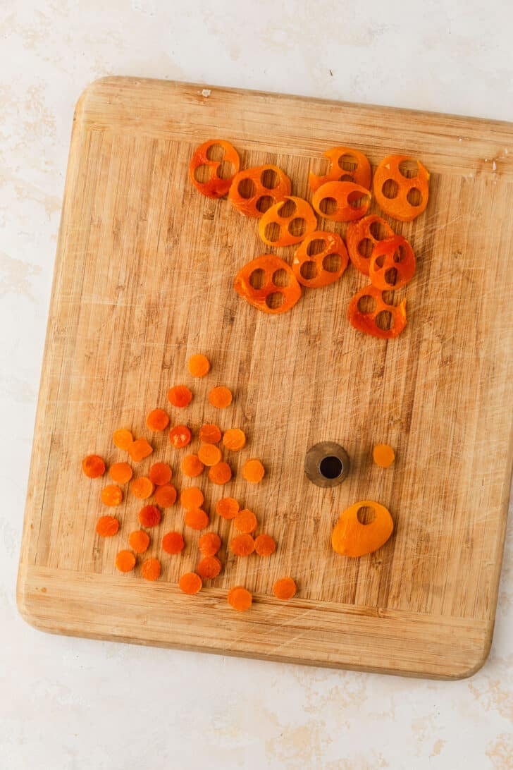 Dried apricots sliced into circles on a wood board.