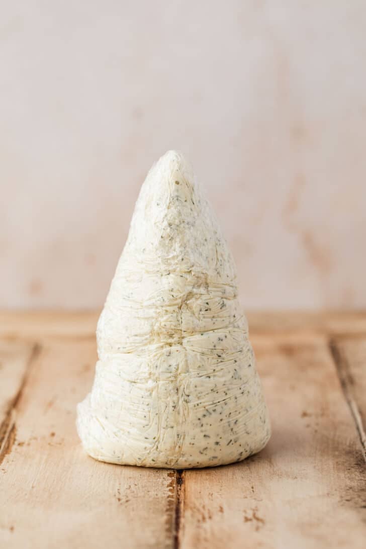 Cheese shaped into a cone on a wood counter.