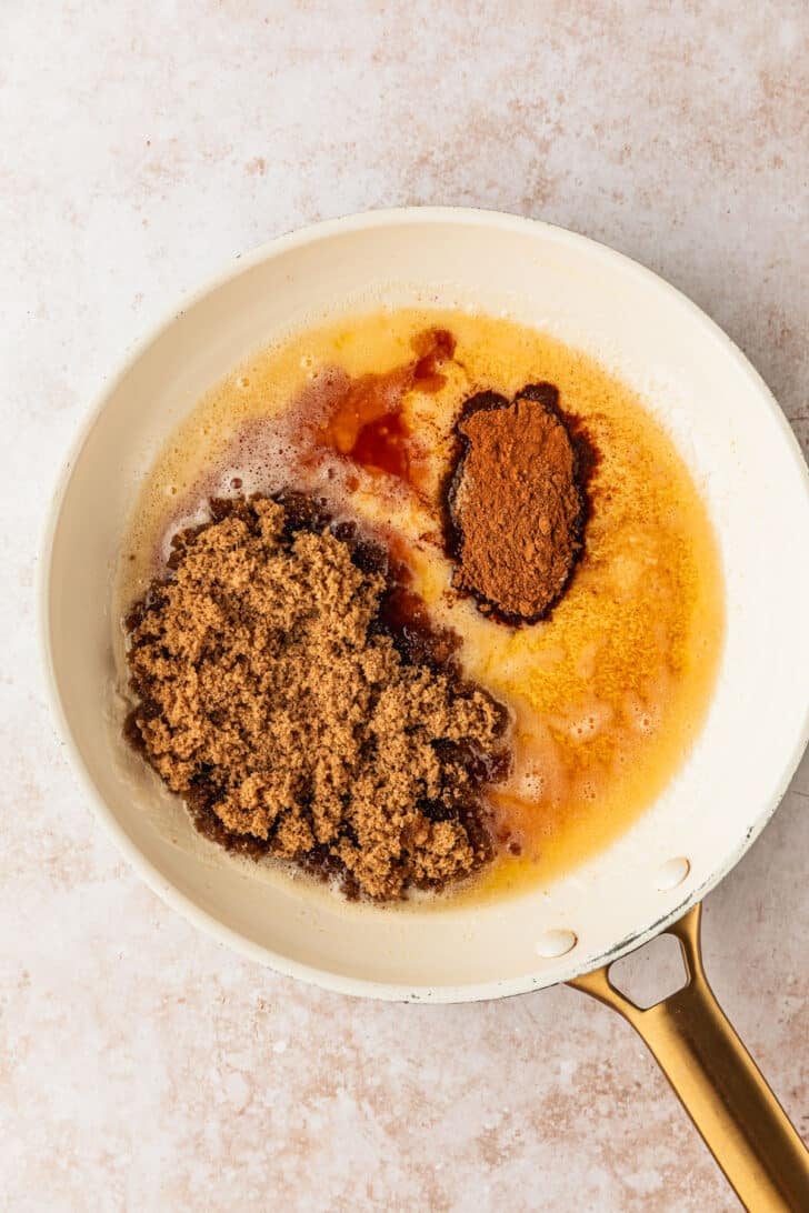 A white pan of brown butter, sugar, spices, and vanilla on a tan counter.