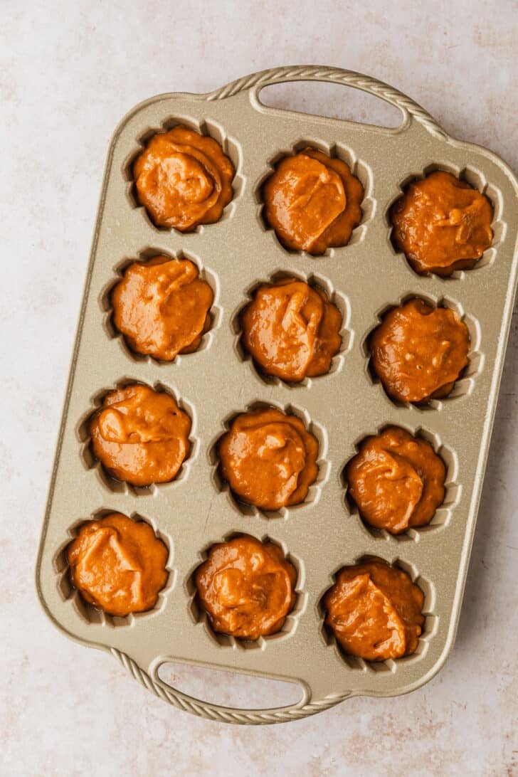 A pan of unbaked pumpkin mini bundt cakes.