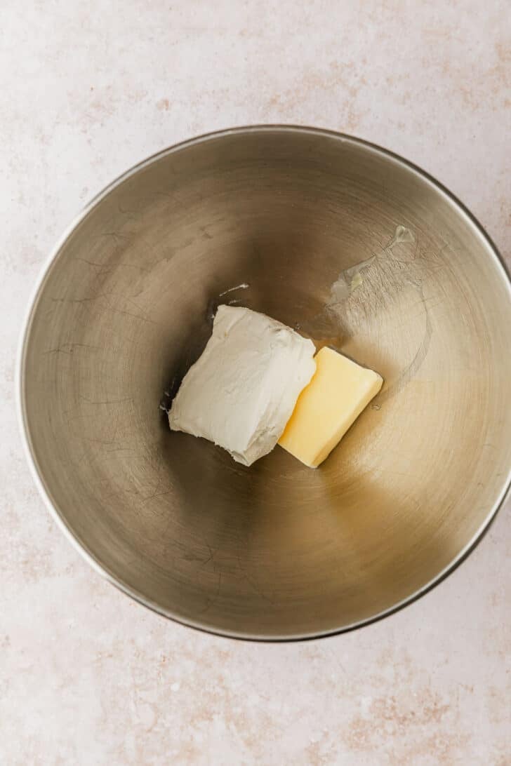 A silver bowl of butter and cream cheese on a tan counter.