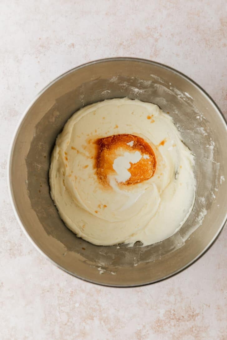 A silver bowl of cream cheese frosting with vanilla for pumpkin mini bundt cakes.