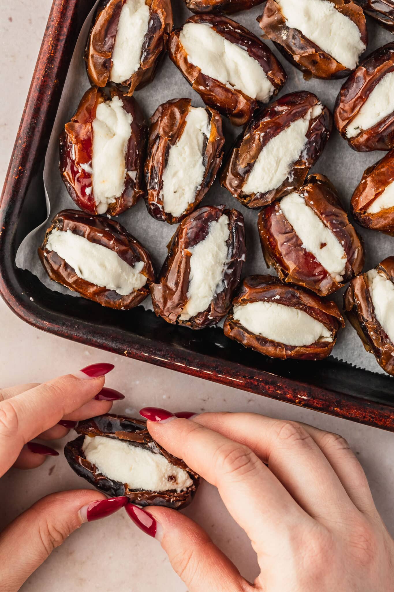 Hands stuffing dried fruit with cheese.