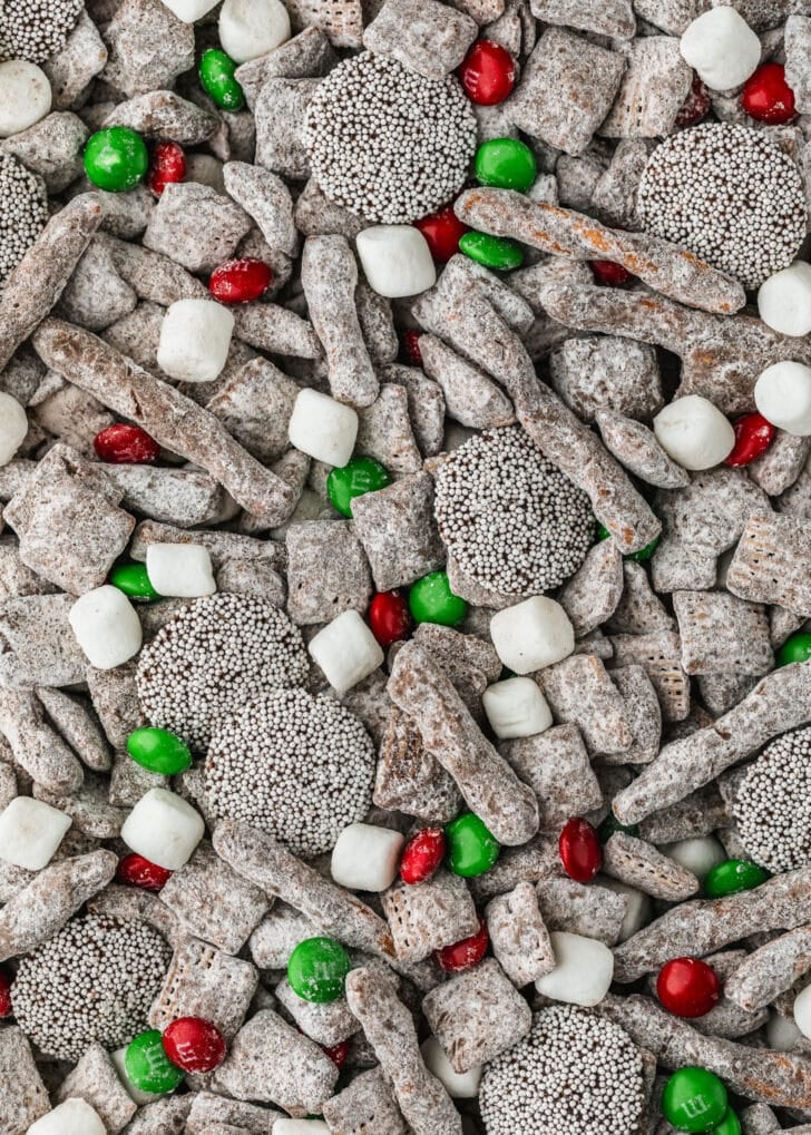 Hot cocoa Christmas puppy chow with M&Ms, pretzels, and sprinkle candies.