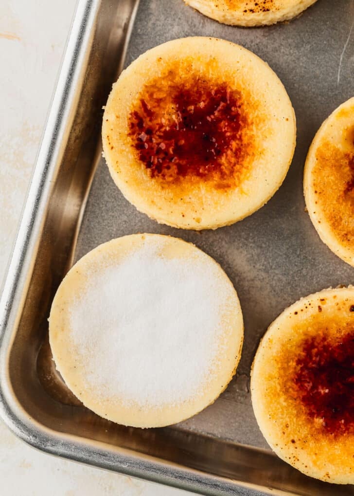 A silver pan of mini creme brulee cheesecakes topped with granulated sugar.