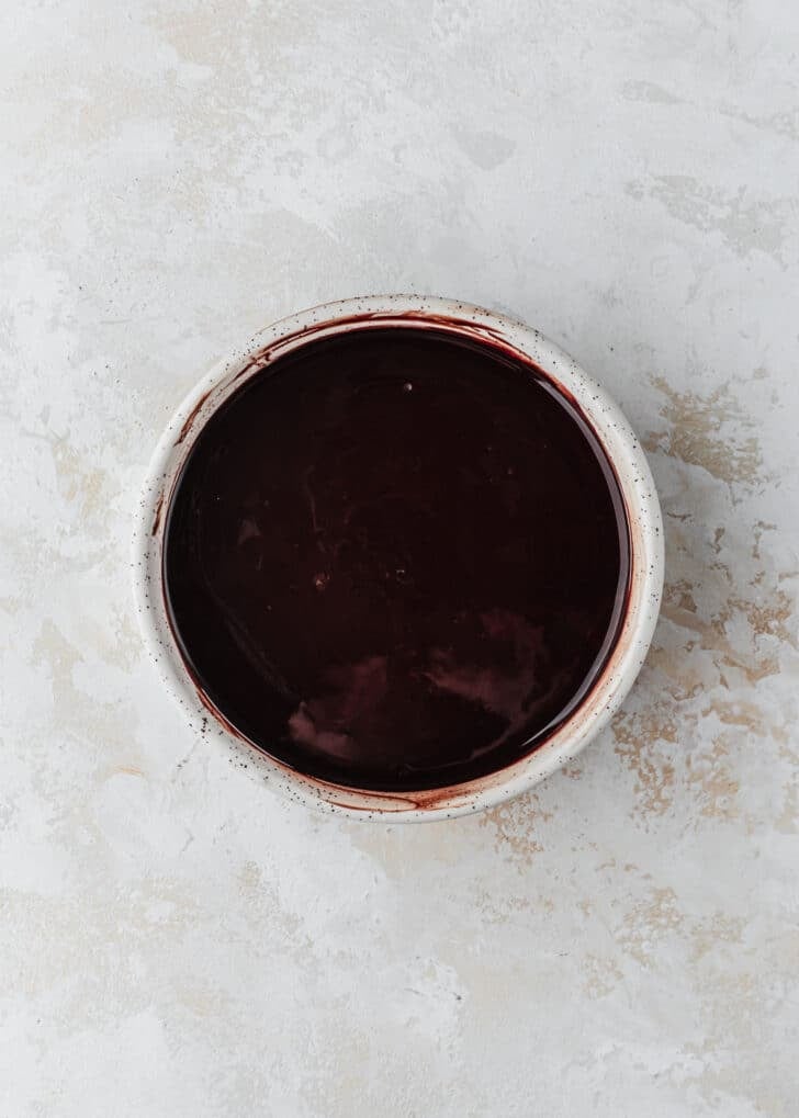 A white bowl of melted chocolate on a white counter.