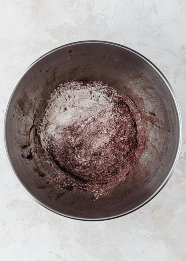 A silver bowl of flour and cocoa powder on a tan counter.
