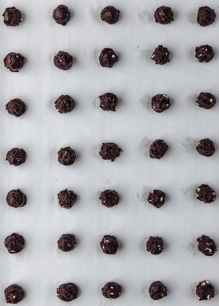 Rows of raw mini chocolate peppermint bark cookies on parchment paper.