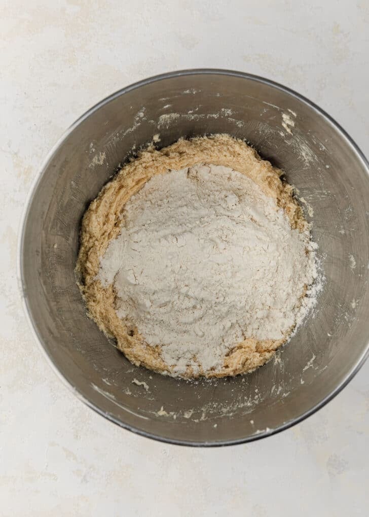 A silver bowl of flour, cornstarch, baking soda, and salt with dough for mini sugar cookies.