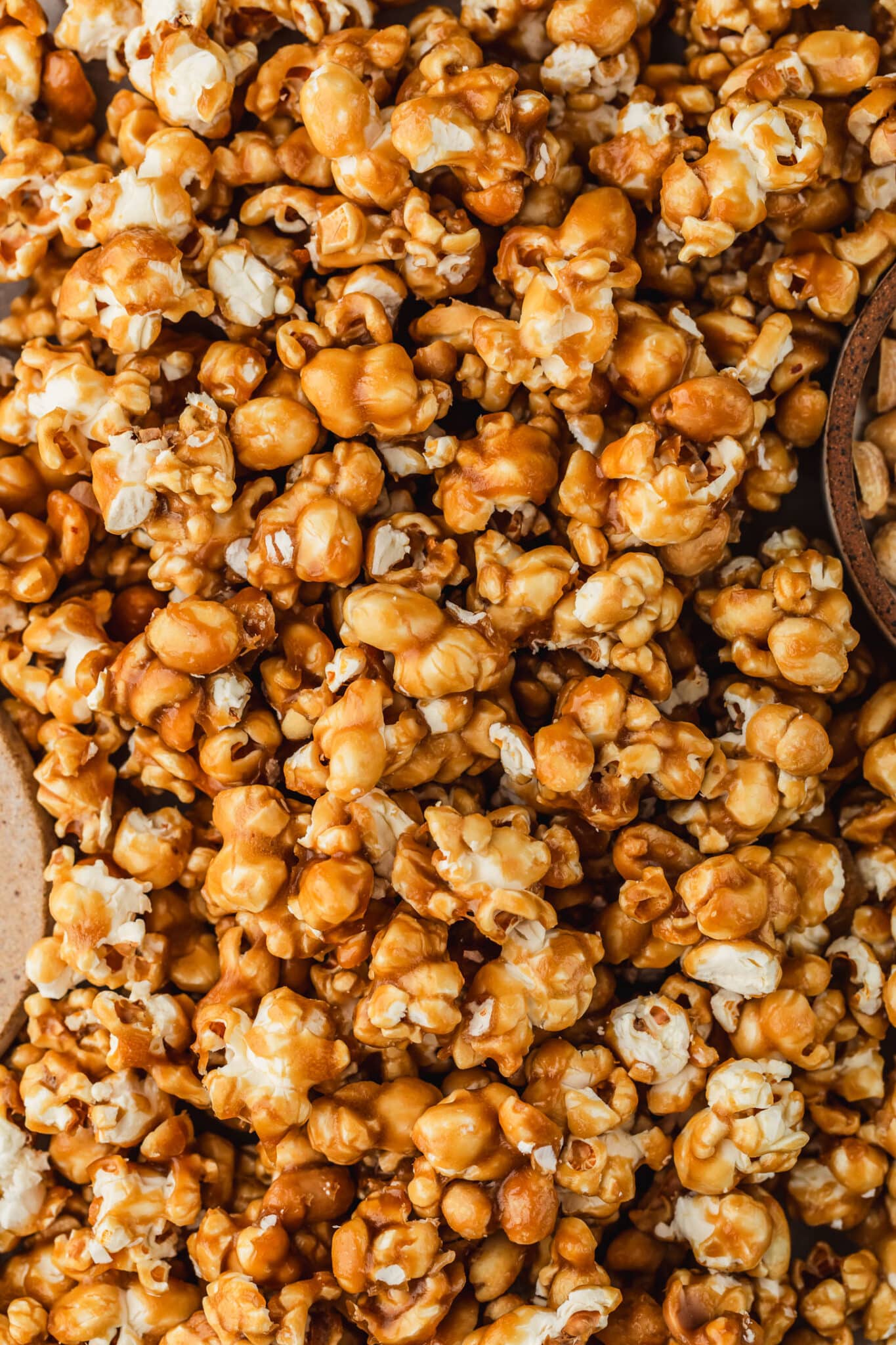 Salted caramel popcorn next to brown bowls of peanuts and flaky salt.