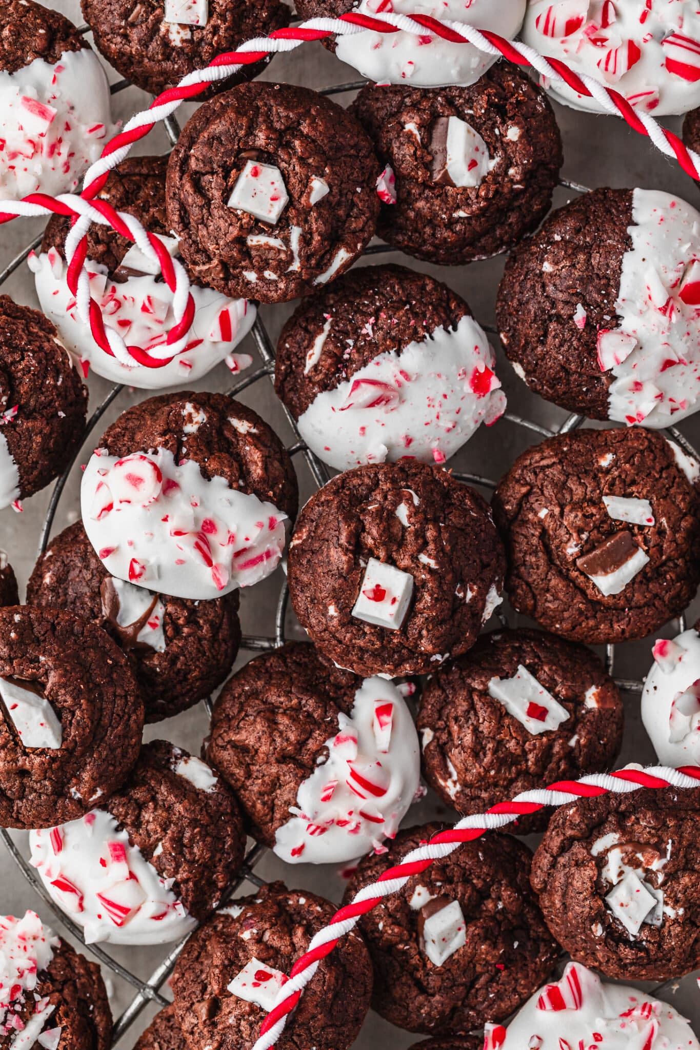 A wire rack of mini chocolate peppermint bark cookies on a grey table.