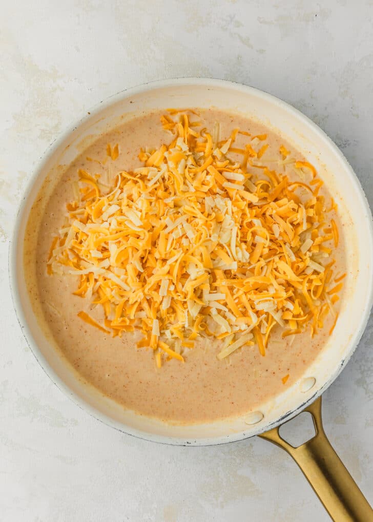 A white pan of sauce and cheese on a white counter.