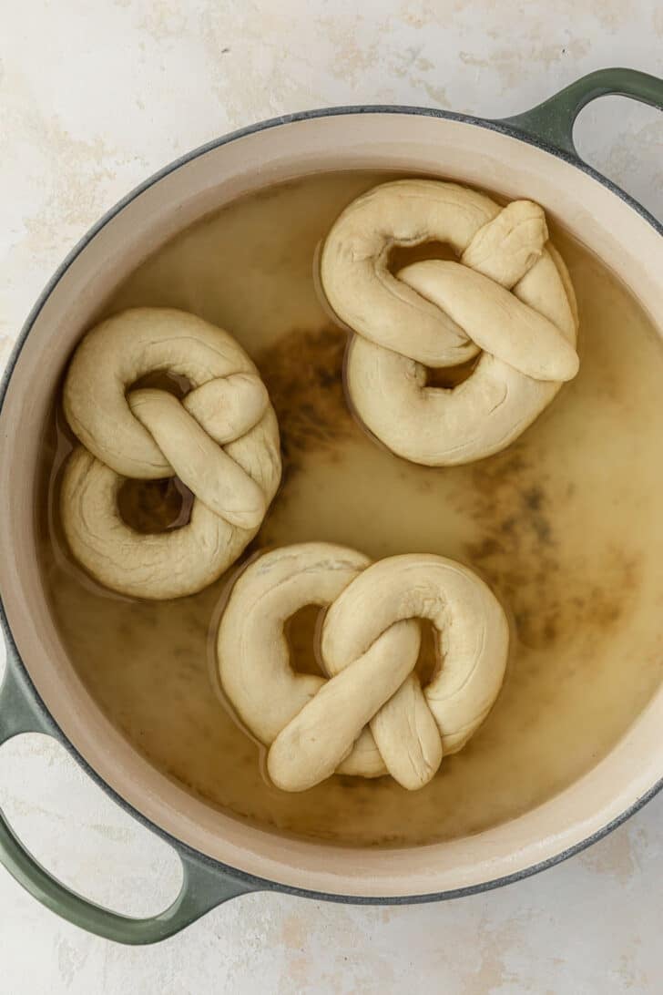 Raw mini pretzels in a pot of a baking soda bath.