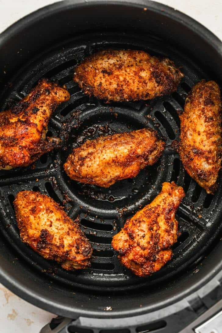 Crispy dry rub chicken wings in an air fryer basket.
