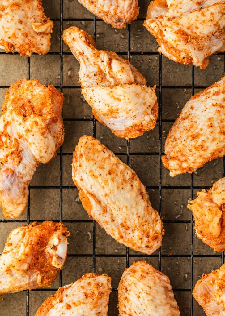 Rows of raw chicken wings on a wire rack.