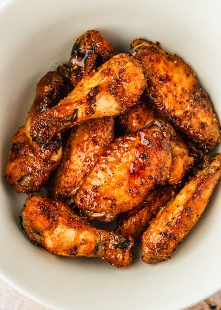 A white bowl of lemon pepper honey wings.