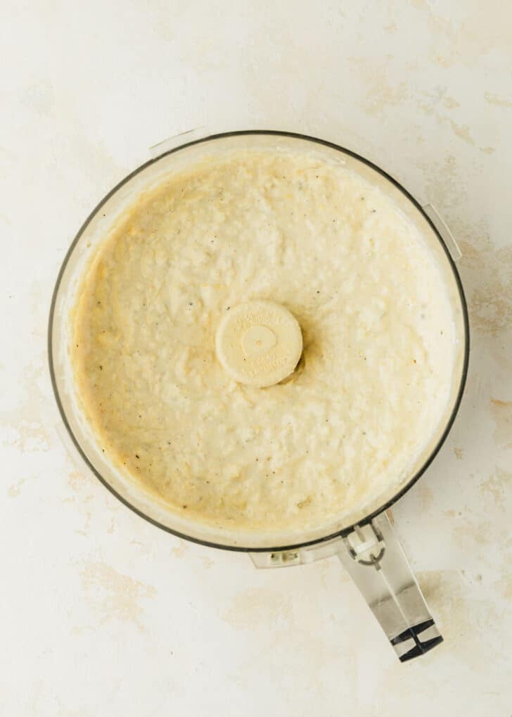 A food processor of white spread on a white and beige counter.
