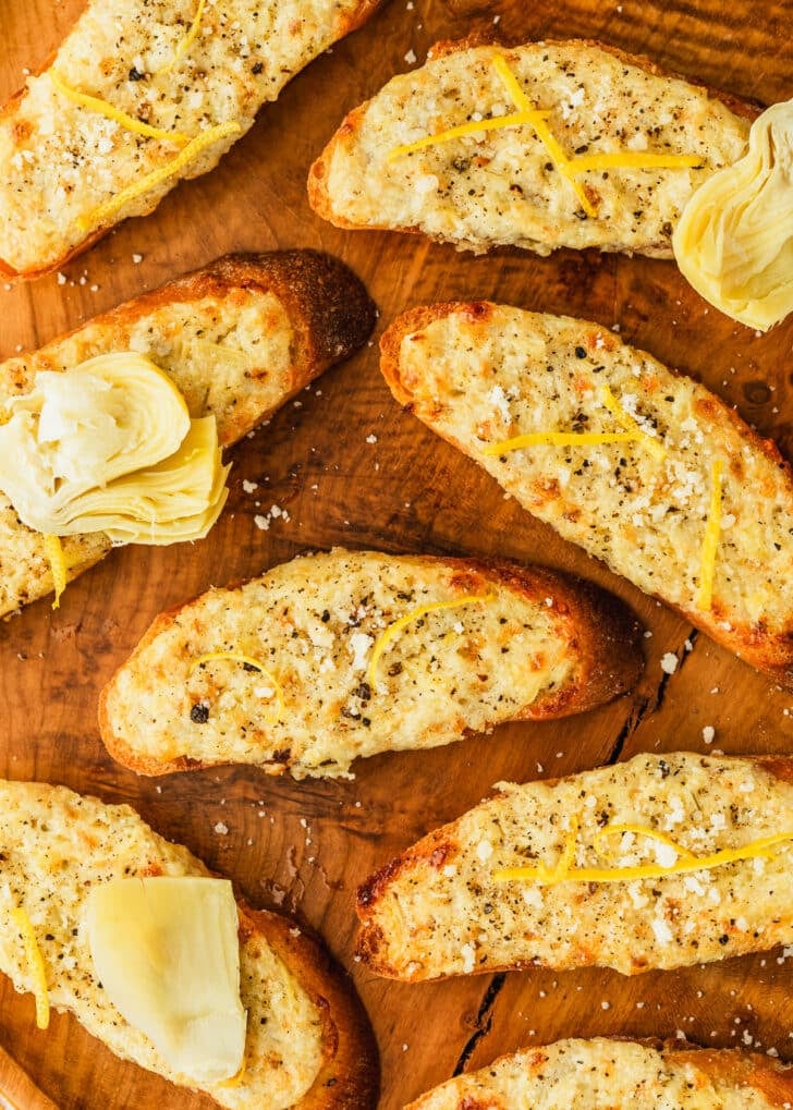 Rows of crostini on a wood platter.
