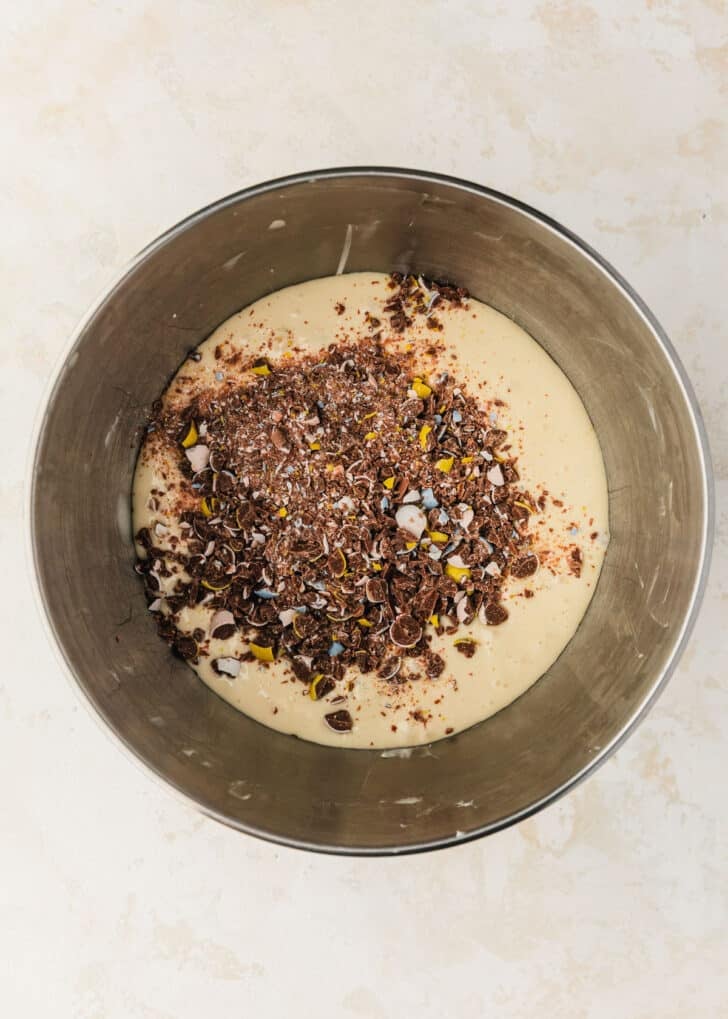 A silver bowl of filling for mini egg cheesecakes on a beige table.