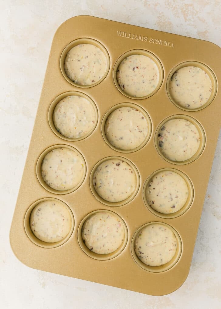 A pan of raw mini egg cheesecakes on a white and beige counter.