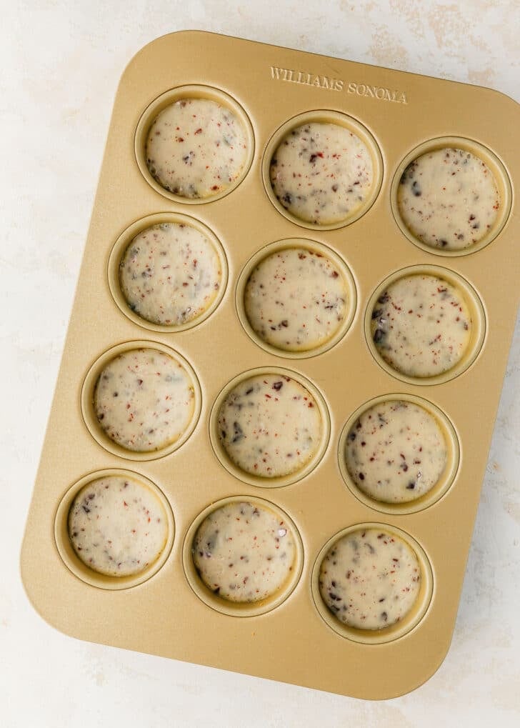 A gold pan of mini egg cheesecakes on a tan table.