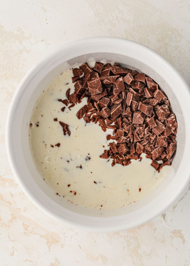 A white bowl of chocolate and cream on a tan counter.