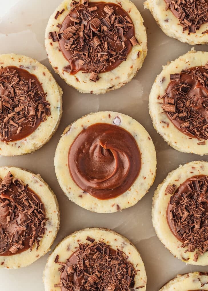 Mini egg cheesecakes with chocolate ganache on a marble platter.