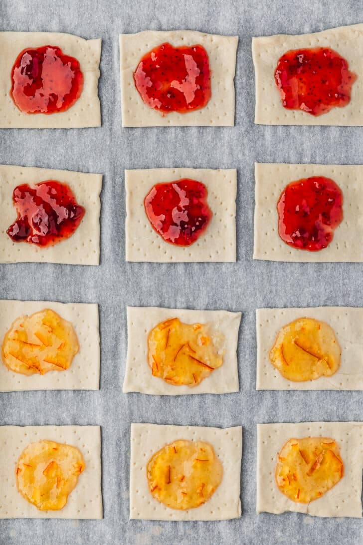 Dough squares topped with strawberry and orange preserves.