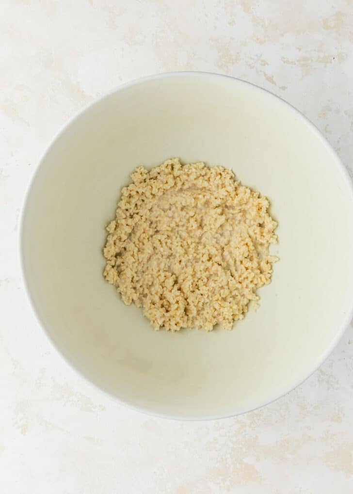 A white bowl of breadcrumbs and milk on a white counter.