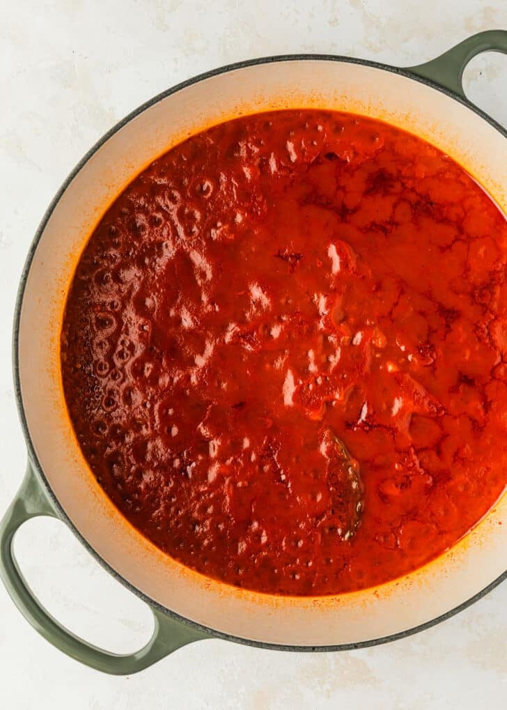 A white pot of tomato sauce for Spanish meatballs.