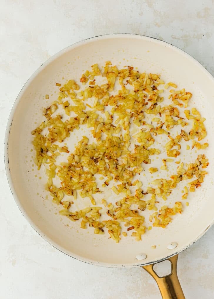 A white pan of sauteed onions on a beige counter.