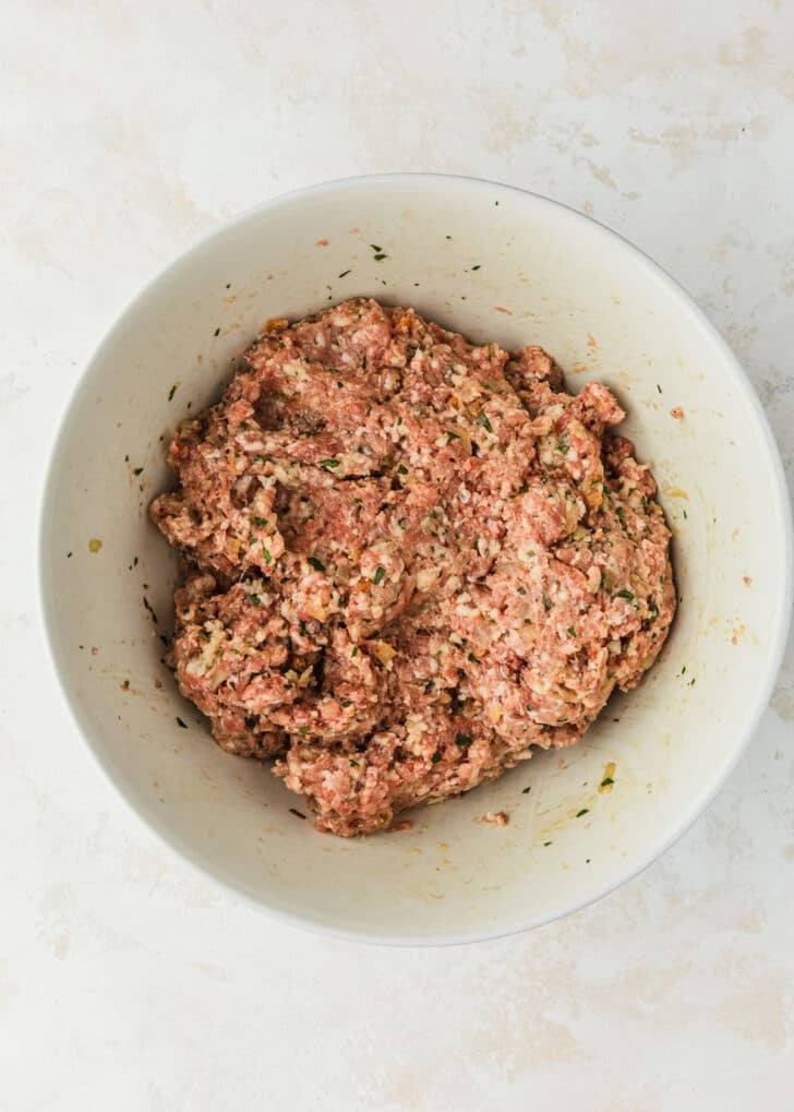 A white bowl of meat mixture for tapas-style Spanish meatballs.
