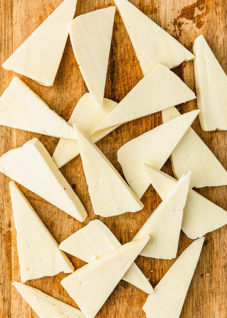 Sliced cheese on a wood board.