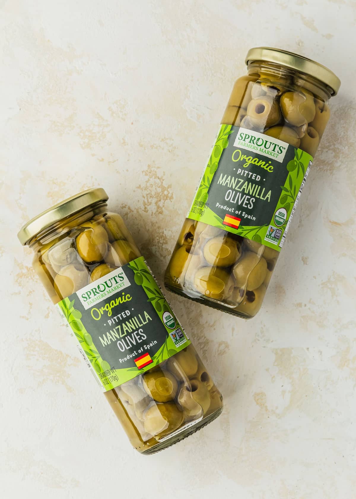 Jars of Manzanilla olives on a beige counter.